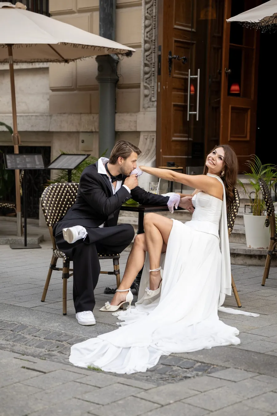 Vőlegény megcsókolja menyasszonya kezét egy hangulatos budapesti kávéházi teraszon — Gáspár Enikő Photography