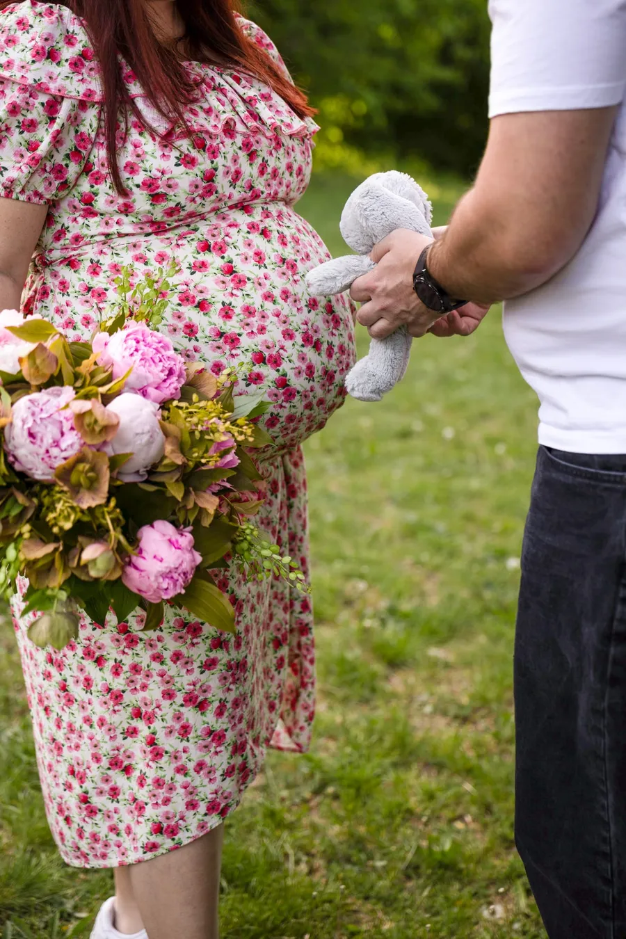 Várandós nő pünkösdi rózsa csokrot tart, párja plüss játékkal áll mellette a parkban — Gáspár Enikő Photography