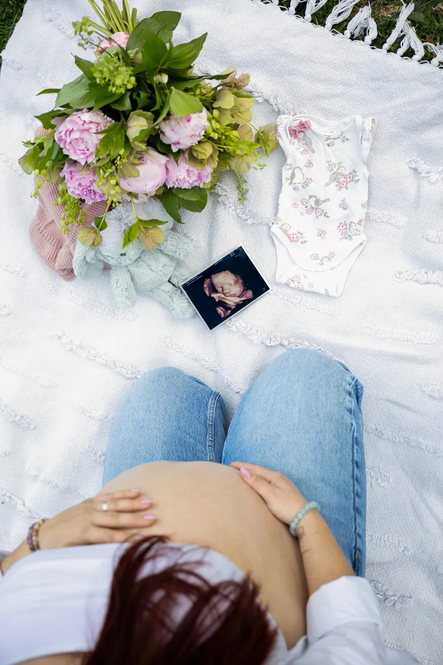 Terhes fotózás felülről: várandós anya takarón fekve, ultrahangképpel és bébi ruhácskával — Gáspár Enikő Photography